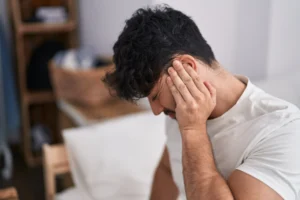 Man sitting at home holding his ear in discomfort due to blocked ears