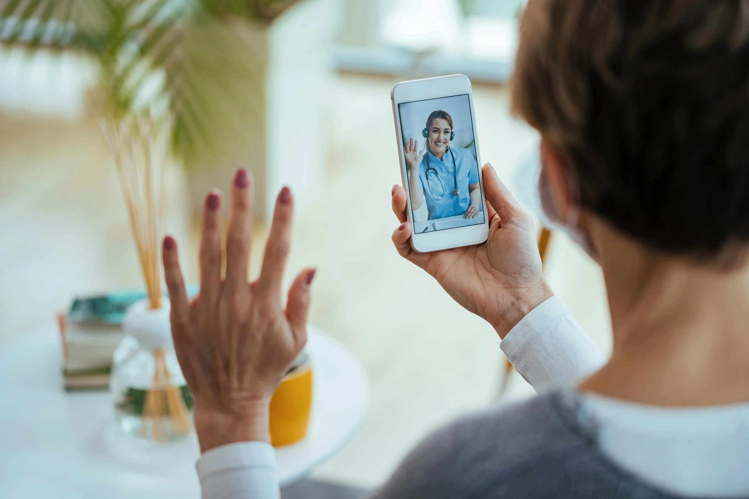 Woman having an online GP appointment by video call with a telehealth doctor on her smartphone at home